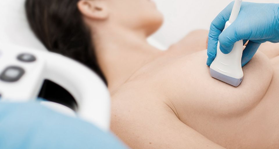 누워있는 여성의 유방에 초음파 기기를 대고 있다